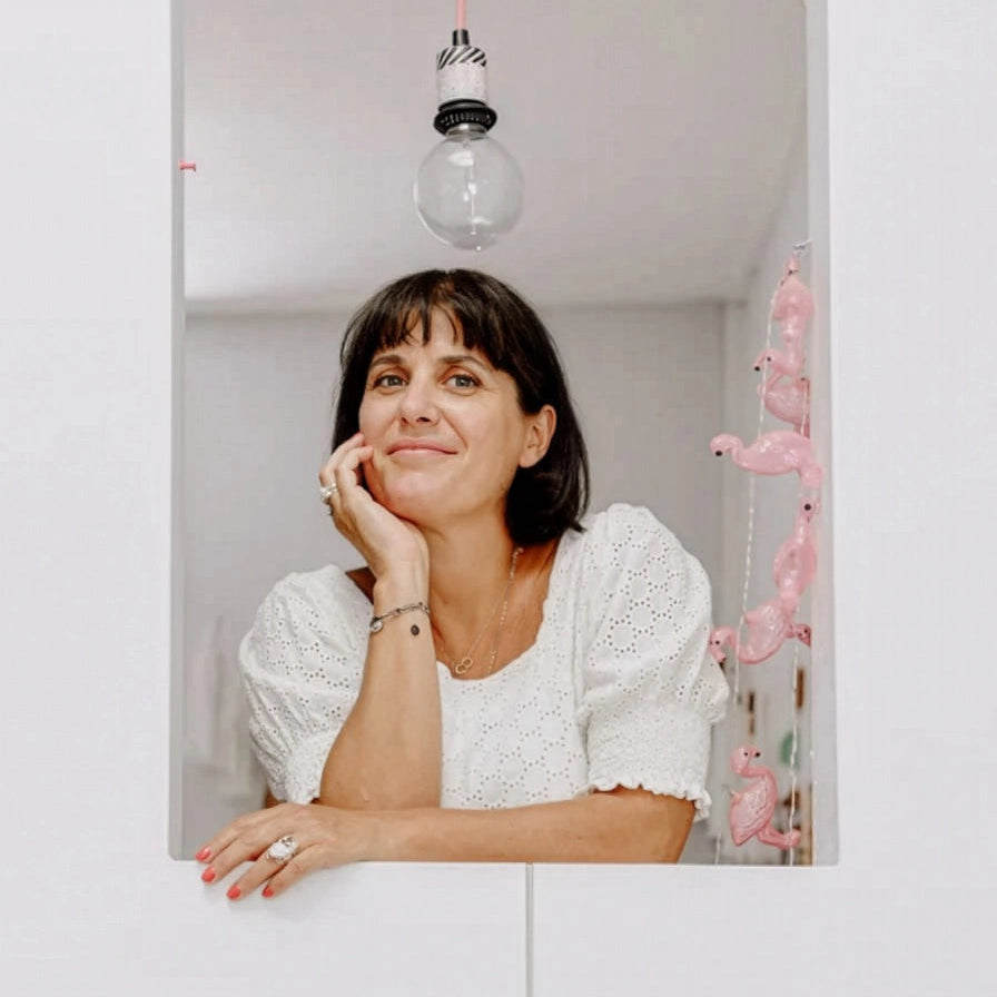 Woman in a white blouse sitting in a room with pink decorations.